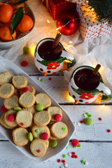 Christmas and new year holiday celebration concept background. Mug of mulled wine with spices, homemade nut cookie, shortbread, xmas tree decoration on wooden table