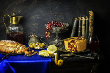 Classic still life with fresh red grapes placed with green olives,bread,fruits pie and tasty drink...