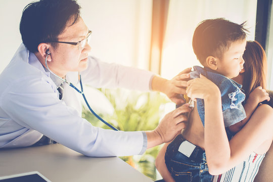 Doctor with stethoscope listening breath of a illness boy in his mother arm