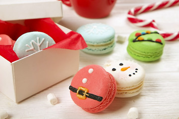 Traditional christmas themed french macaroons sweets in the form of snowman, snowflake, christmas tree and santa's belly with candy cane and white marshmallows on the white wooden table.  Close up.