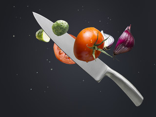 A knife cutting cucumber, tomato and onion
