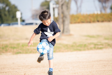 公園でサッカーをする子供