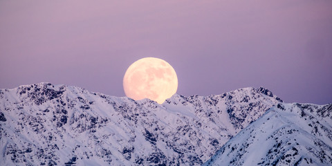 full moon rising in the evening sky in the Swiss Alps over a winter mountain landscape near Klosters © makasana photo
