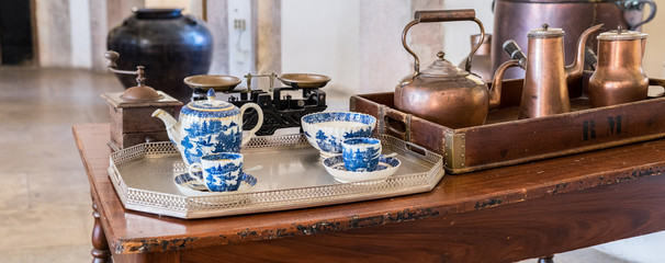 Fototapeta na wymiar China tea set on table at typical portuguese kitchen equipped with copper kitchenware