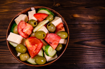 Greek salad in a bowl on wooden table. Top view