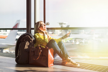 Hipster girl waiting for flight in airport and listening to music