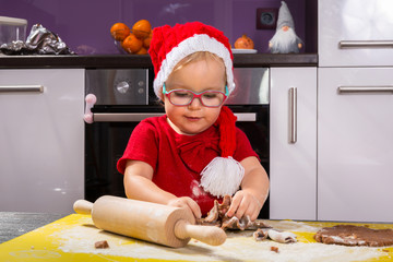 Cute little girl with roller pin preparing Christmas cookies - obrazy, fototapety, plakaty