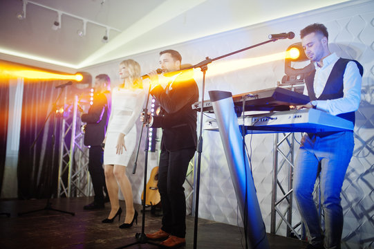 Musicial music live band performing on a stage with different lights.
