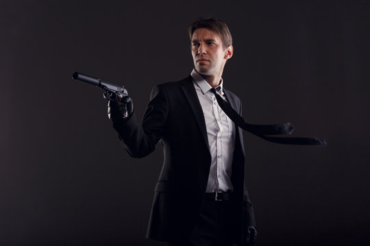 Photo of man with developing tie in leather gloves with gun