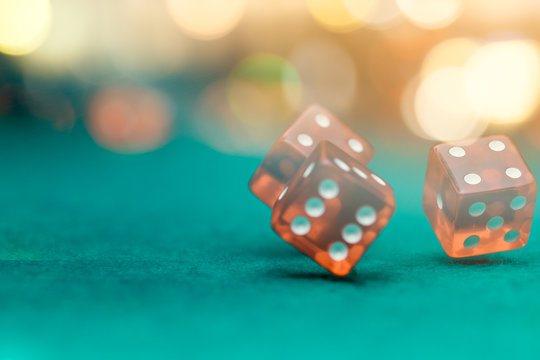 Photo of several red dice falling on green table in casino