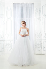 Fototapeta na wymiar A sweet bride in a chic dress in a beautiful light interior.