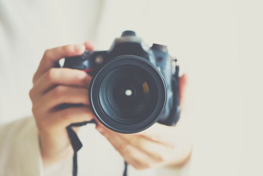 Girl hands holding photo camera with vintage color effect, white background, copy space