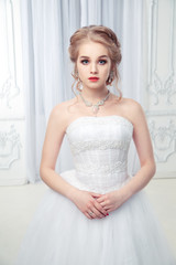 Fototapeta na wymiar A sweet bride in a chic dress in a beautiful light interior.
