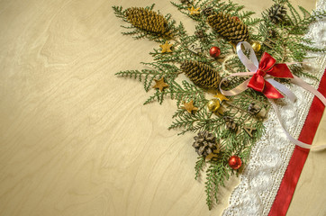 Christmas tree is collected from twigs of thuja with fir cones and chocolate balls,red and lace tape at an angle on  plywood