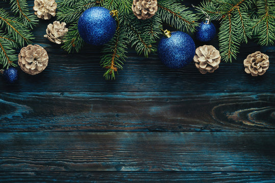 New Year and Christmas decorations Pine tree branches, cones, blue Christmas toys on a wooden background.