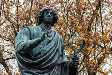 Monument to Nicolaus Copernicus (1853) in academic dress holding an astrolabe, pointing to the heavens to symbolize his celestial studies. The astronomer wearing a red Santa's hat today. Torun, Poland