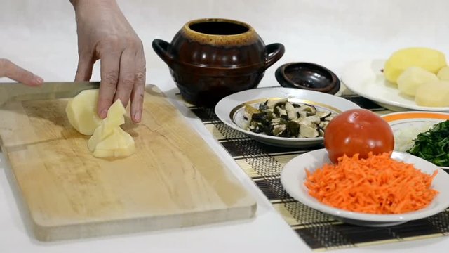 Slicing potatoes for hot dishes roast in a clay pot