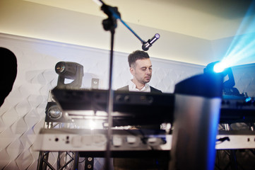 Musicial music live band performing on a stage with different lights. Keyboardist play.