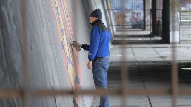 Graffiti. A young guy draws on the wall.