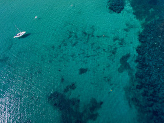 Vista aerea di una barca ormeggiata che galleggia su un mare trasparente. Immersioni relax e vacanze estive. Coste e fondale marino