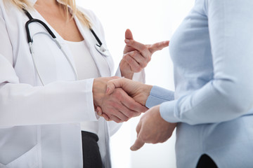 Healthcare and medical concept - doctor with patient in hospital. Handshake.