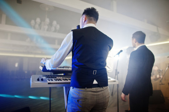 Musicial music live band performing on a stage with different lights. Keyboardist play.