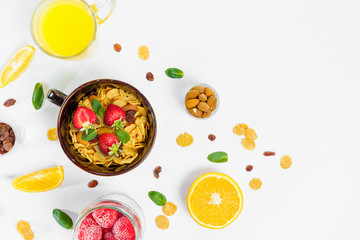 Cereal, morning breakfast, corn flakes, raisins, almonds, mint leaves, orange juice, strawberry, top view, white background, flat lay. The concept of healthy, proper nutrition, ditox.
