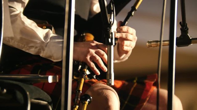 Bagpipe player in a kilt plays musical instrument at the stage