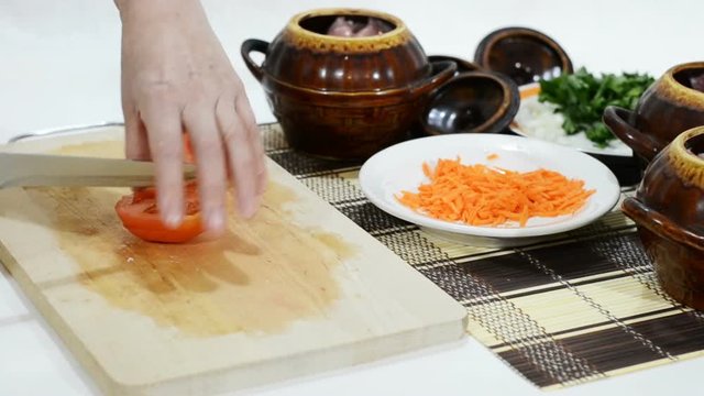 Slicing tomatoes for hot dish in a clay pot