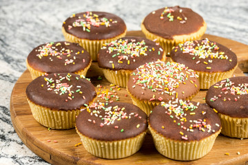 Vanilla cupcakes with chocolate cream and colorful sprinkles