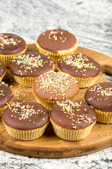 Vanilla cupcakes with chocolate cream and colorful sprinkles