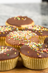 Vanilla cupcakes with chocolate cream and colorful sprinkles