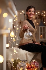 Young woman at fireplace with christmas lights