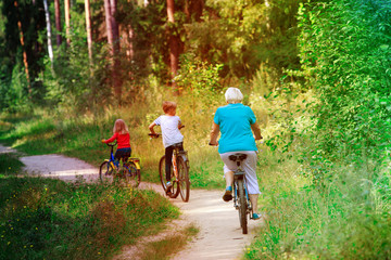 Fototapeta premium active senior grandmother with kids riding bikes in nature