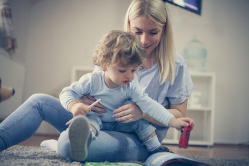 Playing with son in living room. Young mother.