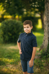 Handsome boy smiling and posing to the photographer. Joyful child walks the park. Sunny weather summer