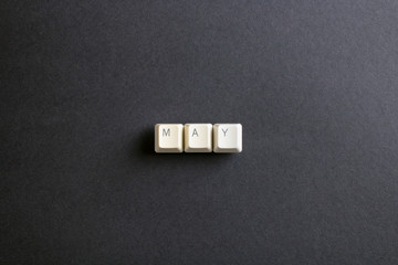May month word is written with computer keys button. Flat lay view from above on the table with computer keyboard keys buttons on a dark background.