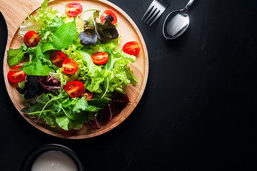 Fresh mixed vegetables salad on a wooden plate