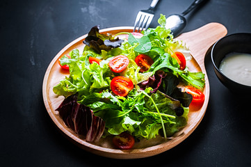 Fresh mixed vegetables salad on a wooden plate