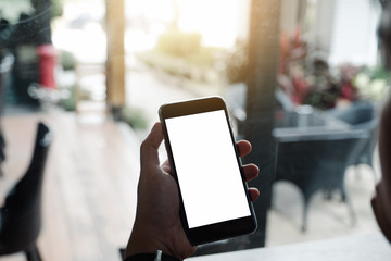 Mockup image of man's hands holding white mobile phone with blank screen in modern cafe