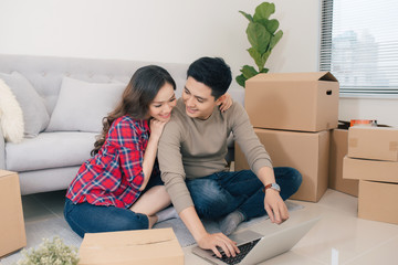 Young asian couple sitting on the floor and looking at the blueprint of new home.