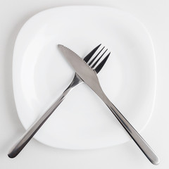 cutlery, fork and knife on an empty white plate