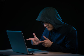 Asian hacker hacking computer network with laptop in dark. Cyber security concept