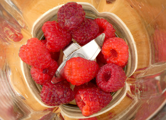 Raspberries in the blender on wooden plank