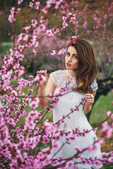 Portrait of young lovely woman in spring flowers. Bride