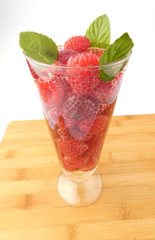 Glass of water full with raspberries isolated on wooden plank