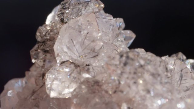 MACRO DOF: Semi-transparent hematite crystal with black streaks running with black streaks running through middle of gemstone. Ice-like precious stone filmed from close distance. Sharp edged hematite.