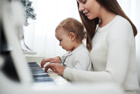 mother and daughter playing white piano, close up wiew