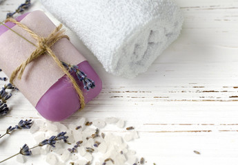 Obraz na płótnie Canvas dry lavender flowers with soap, towel and sea salt on vintage wooden table. spa treatments