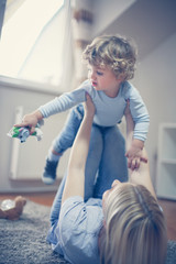 Happy mother have play with little boy in living room. On the move.